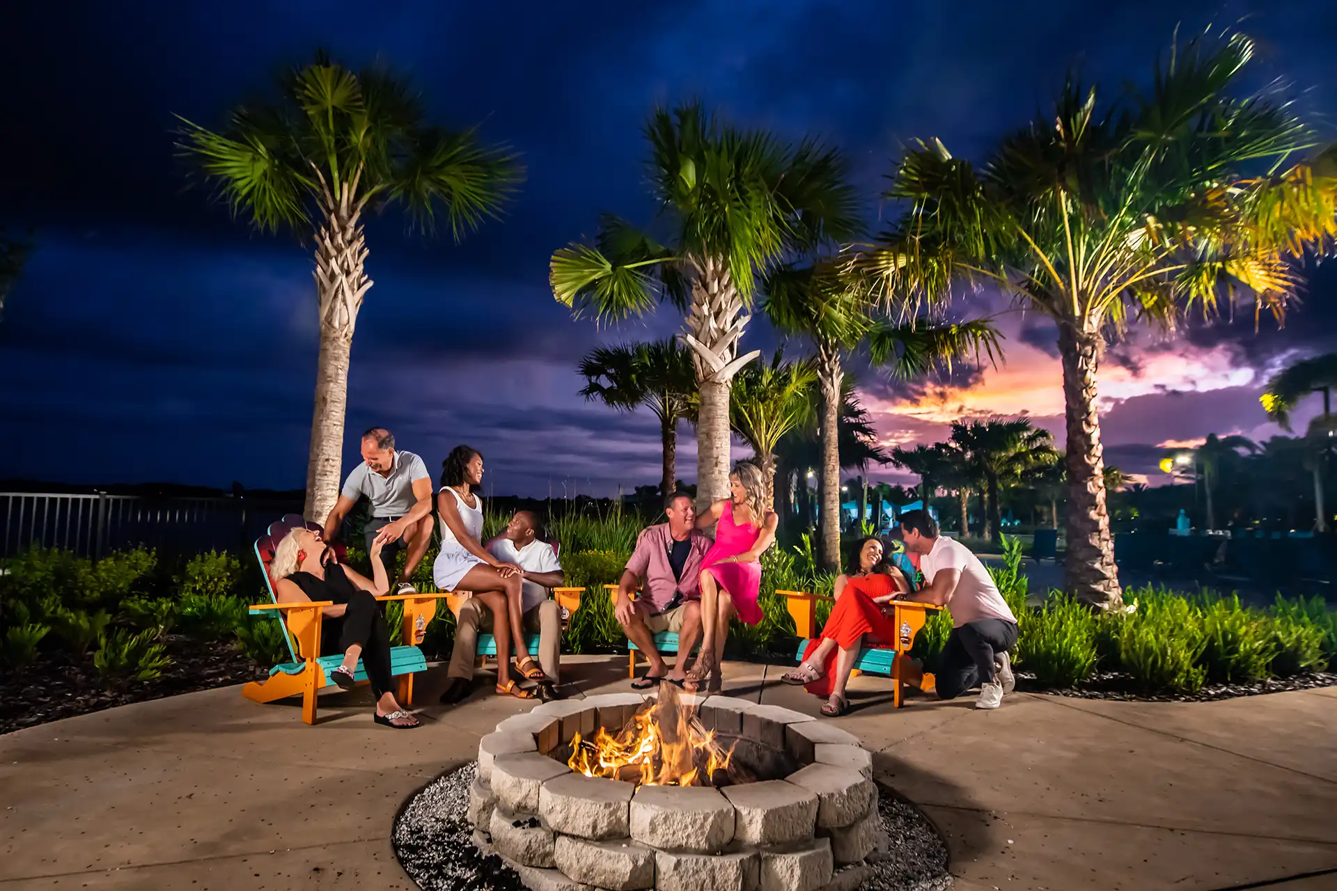 Couples sitting around a fire pit at night